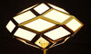 Eine stehende Lampe mit einem mattglas Lampenschirm, der zarte geometrische Muster zeigt.